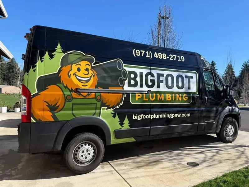 Side view of Bigfoot Plumbing wrapped service van in a Sandy, Oregon driveway — licensed plumber CCB# 257405 serving Sandy, Boring & Gresham OR